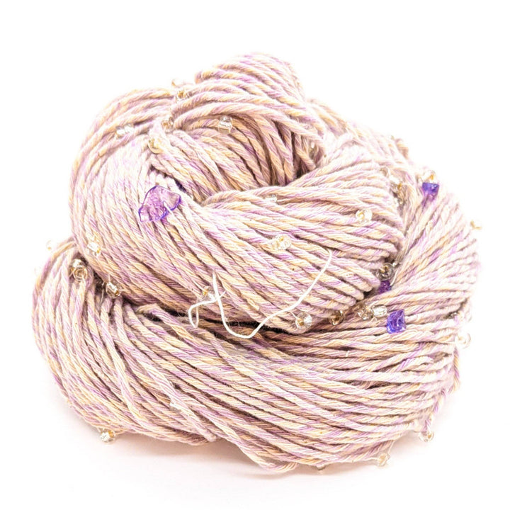 Chakra beaded yarn in spirituality in front of a white background. Light purple and white yarn with light purple beads and crystals throughout. 