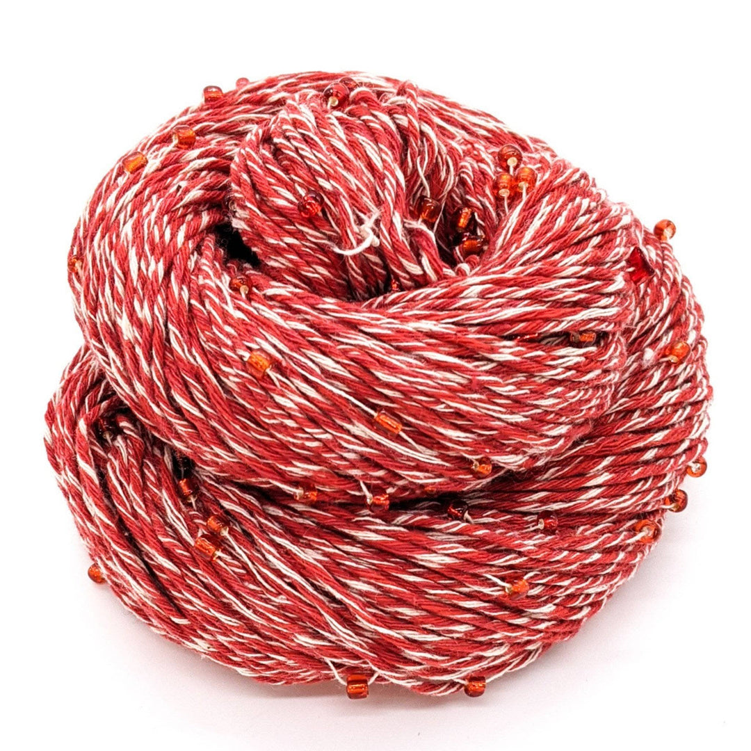 Stability chakra beaded cotton yarn. Red and white with red beads throughout; sitting in front of a white background. 