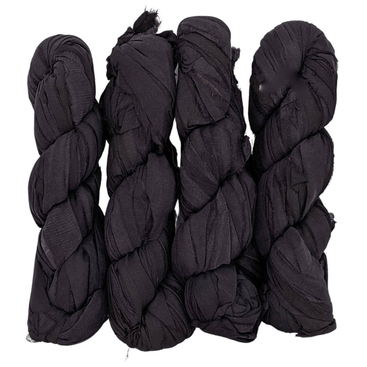 4 skeins of black ribbon yarn in front of a white background.