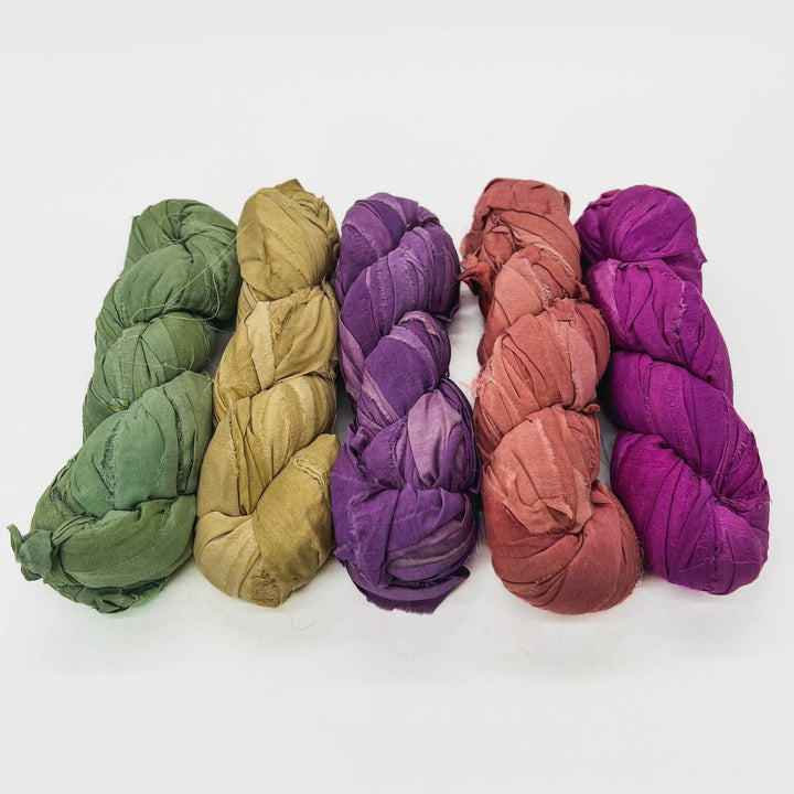 Vintage Chic chiffon ribbon yarn ombre pack in front of a white background. Left to right: dark sage green, muted yellow, medium purple, salmon, magenta. 