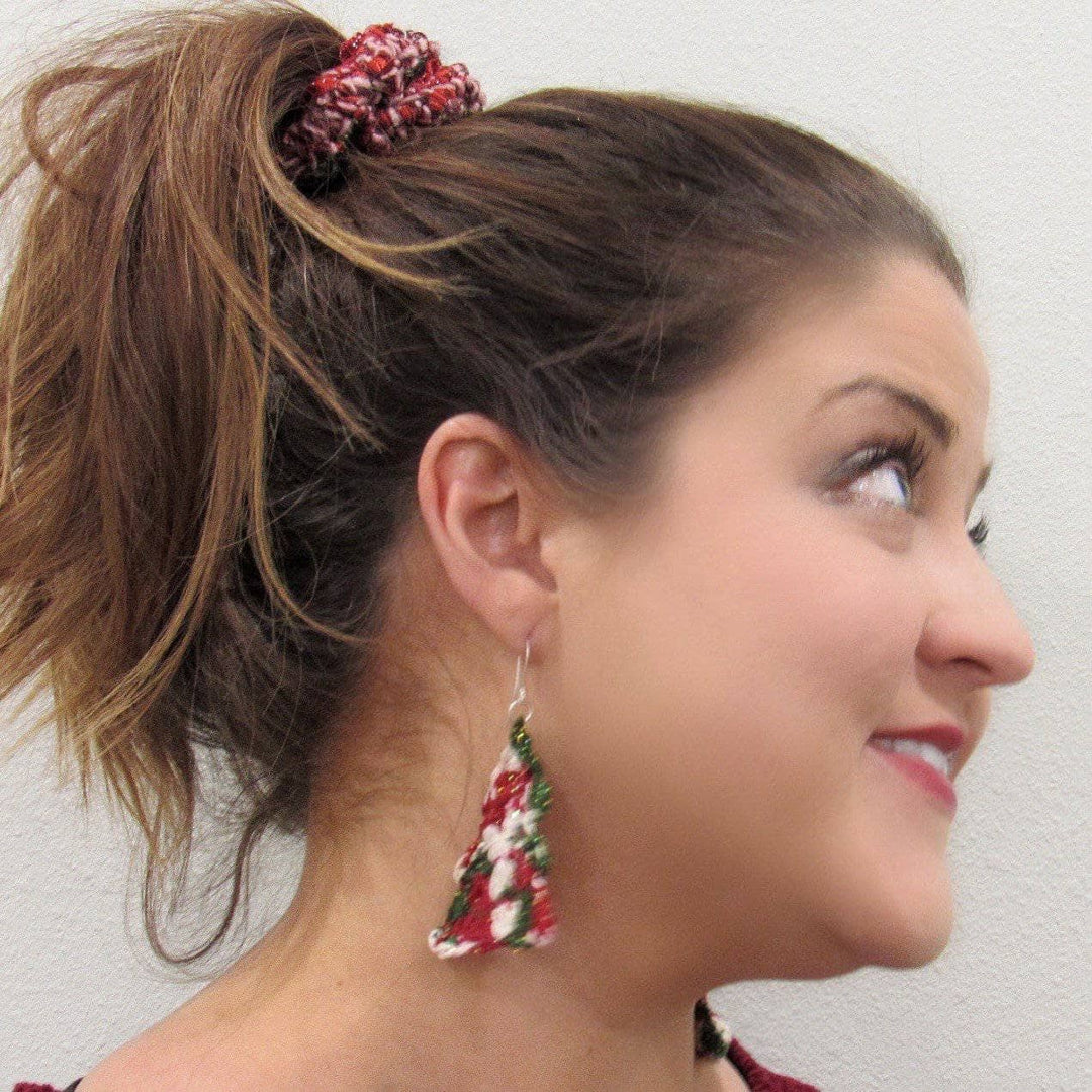 A women wearing green, white and red sparkle Christmas tree yarn earrings