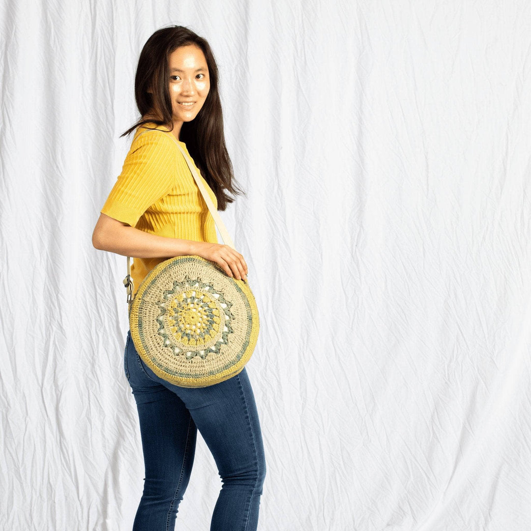 Girl wearing Circle Banjo Bag Crochet Kit with yellow shirt on a white background
