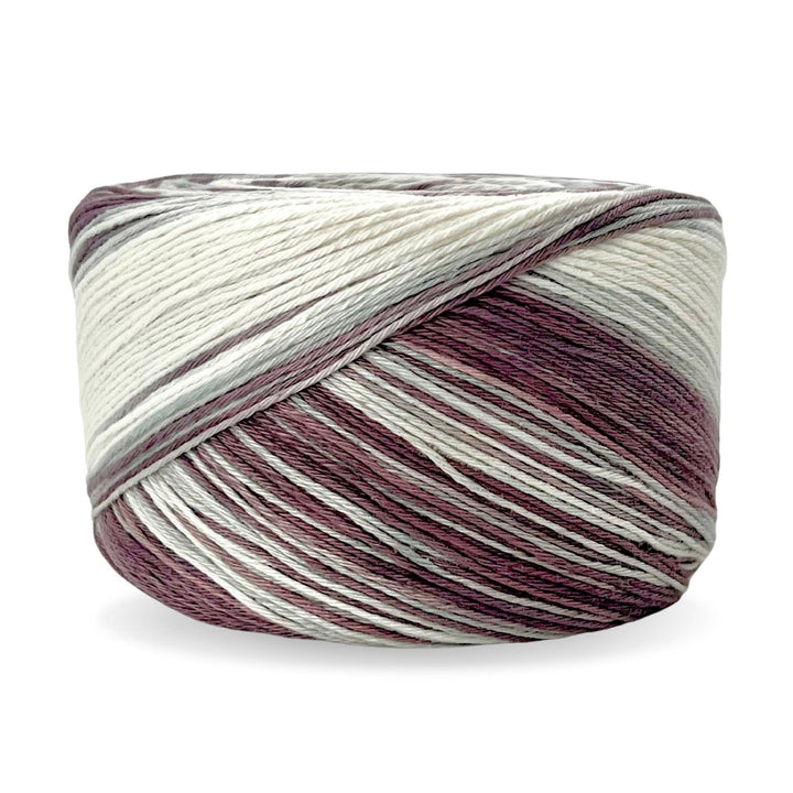 Cake of circulo whoopee blackberry cotton yarn in front of a white background (muted purple, grey, and white tonal yarn).