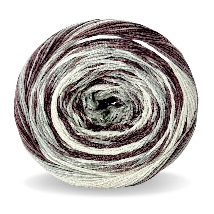 Cake of circulo whoopee blackberry cotton yarn in front of a white background (muted purple, grey, and white tonal yarn).
