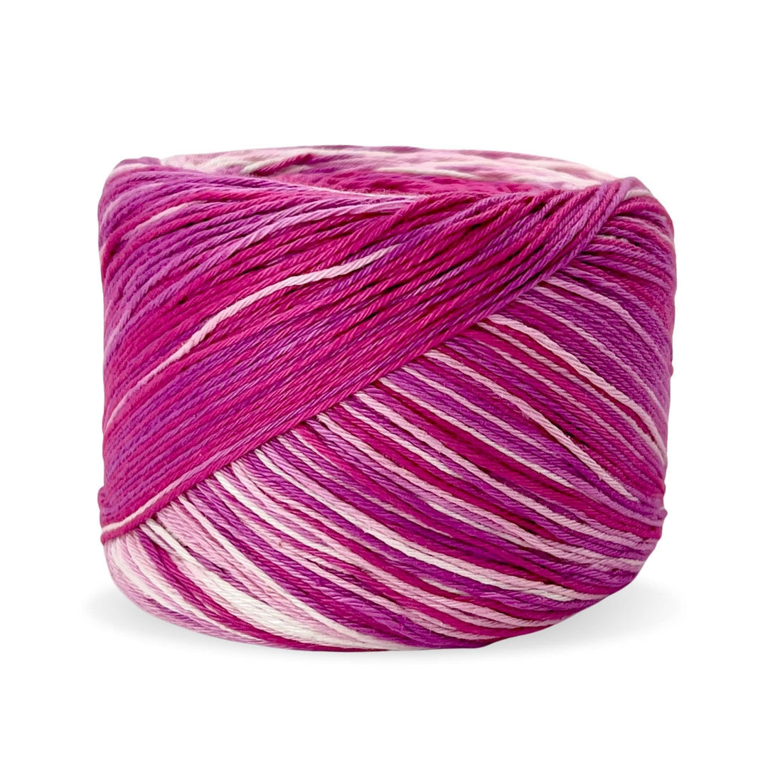 Cake of circulo whoopee lychee cotton yarn in front of a white background (magenta, fuchsia, and blush tonal yarn).