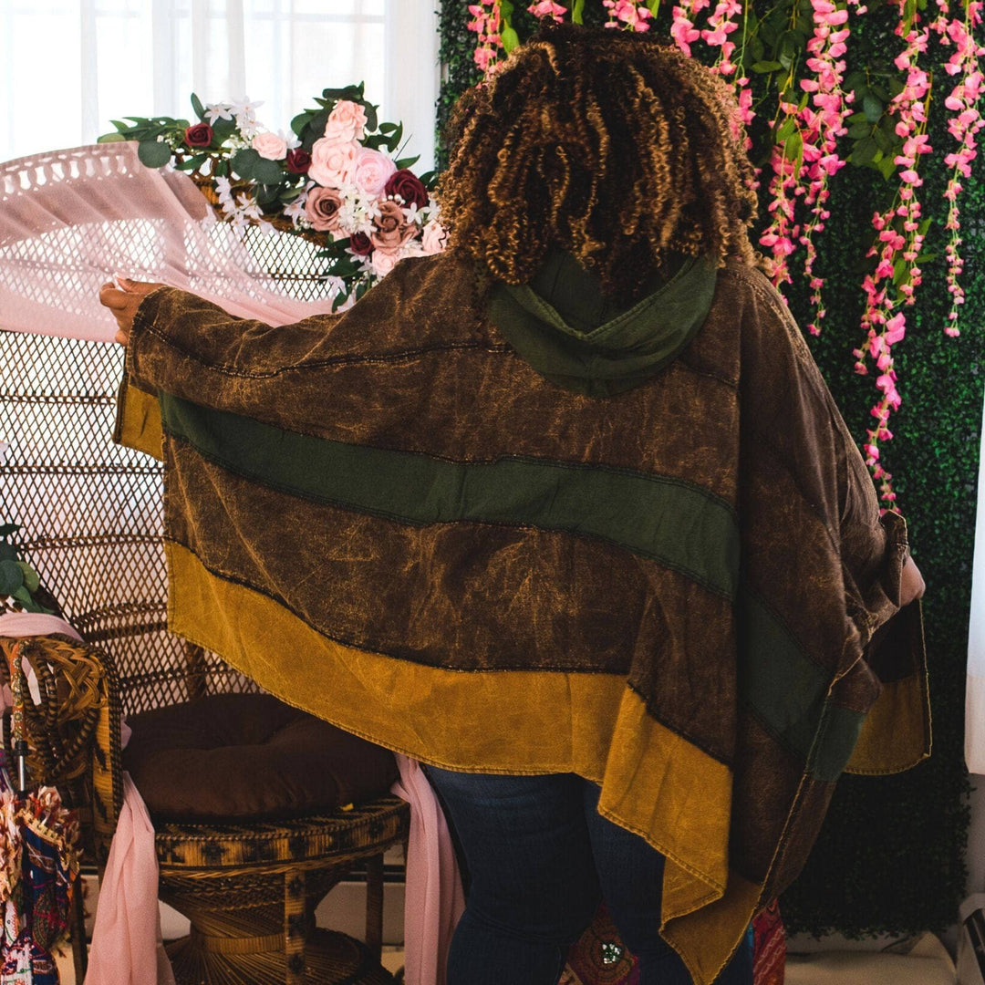 Back view of model wearing green claire hooded poncho in front of a colorful background.