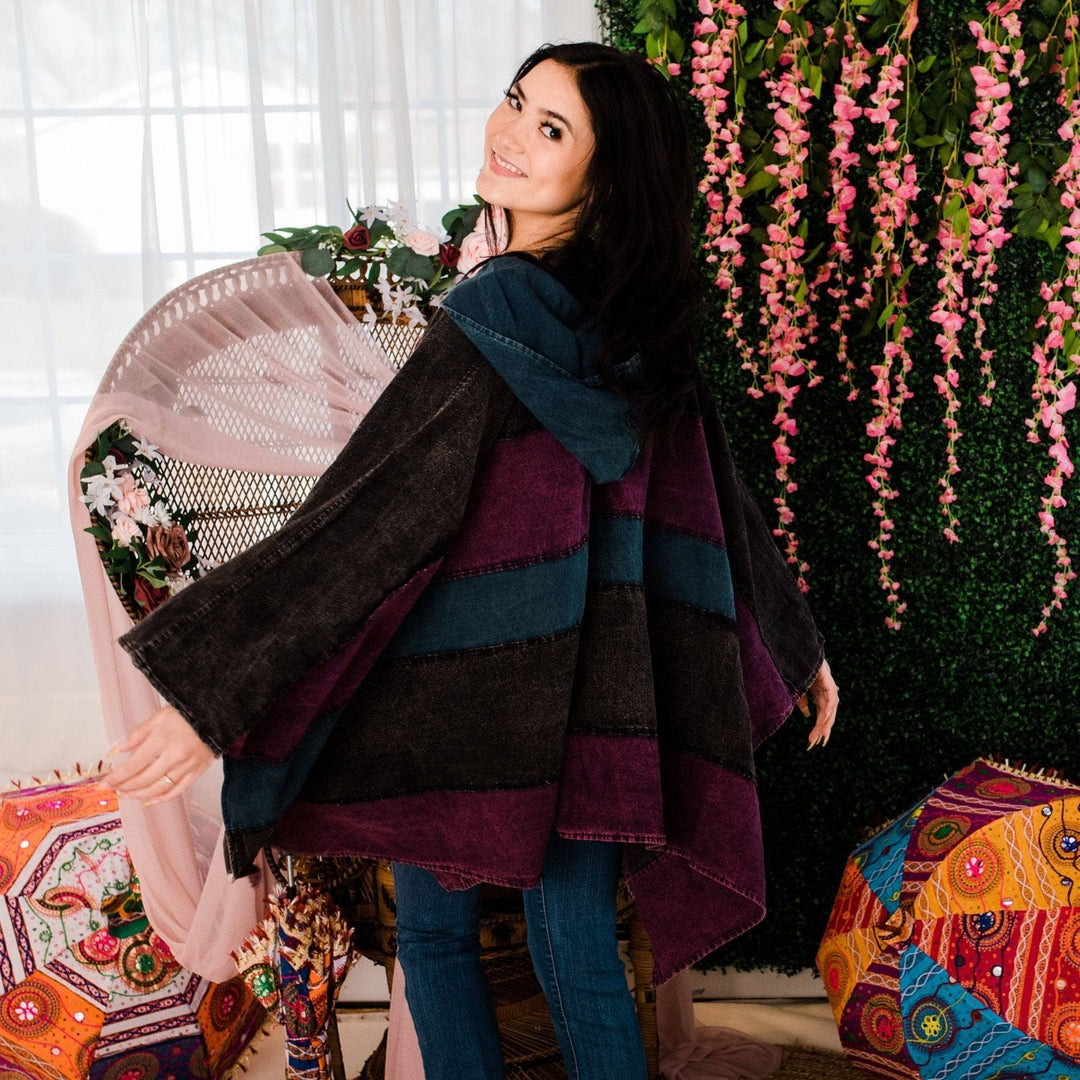 Model wearing purple claire hooded poncho in front of a colorful background.
