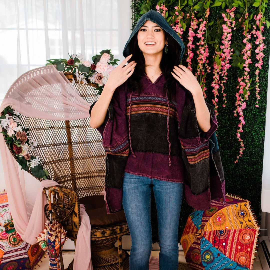 Model wearing purple claire hooded poncho in front of a colorful background.