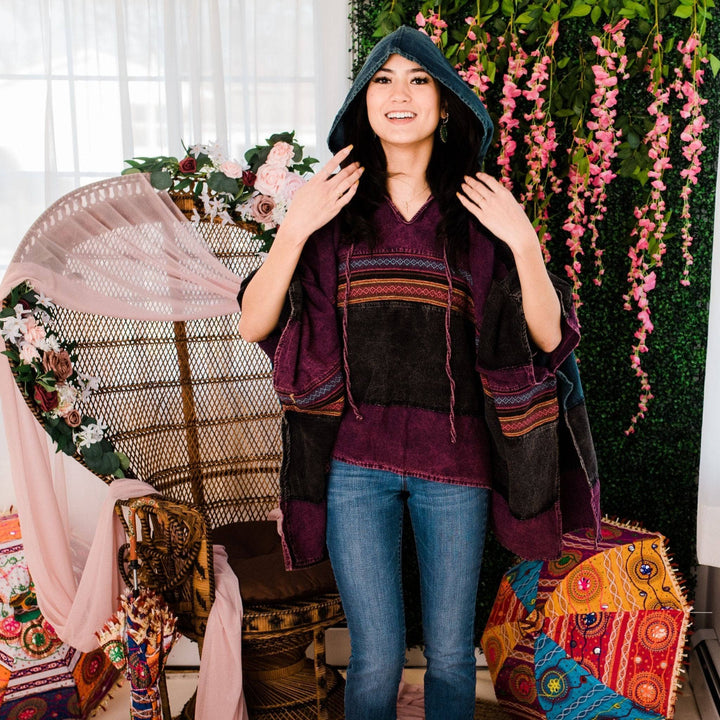Model wearing purple claire hooded poncho in front of a colorful background.