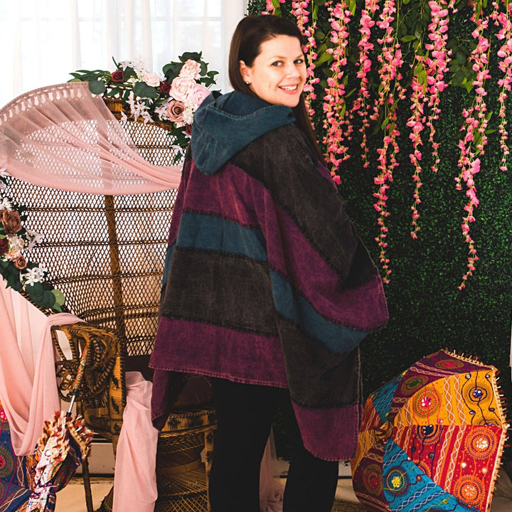 Model wearing purple claire hooded poncho in front of a colorful background.