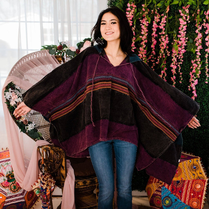 Model wearing purple claire hooded poncho in front of a colorful background.