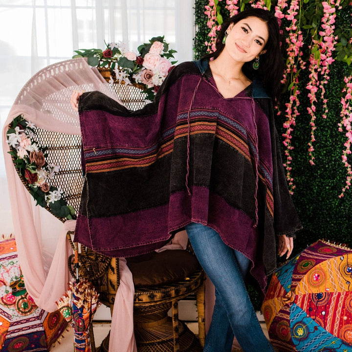Model wearing purple claire hooded poncho in front of a colorful background.