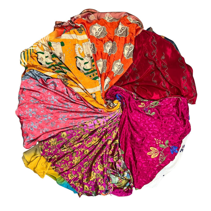 Color wheel of skirts made up of warm colored sari wrap skirts on a white background. 