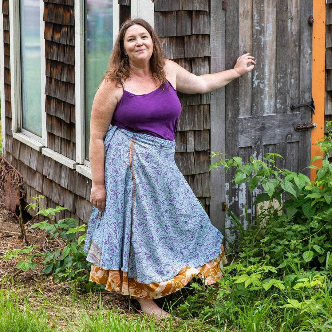A woman outdoors wearing a patterned skirt and purple top