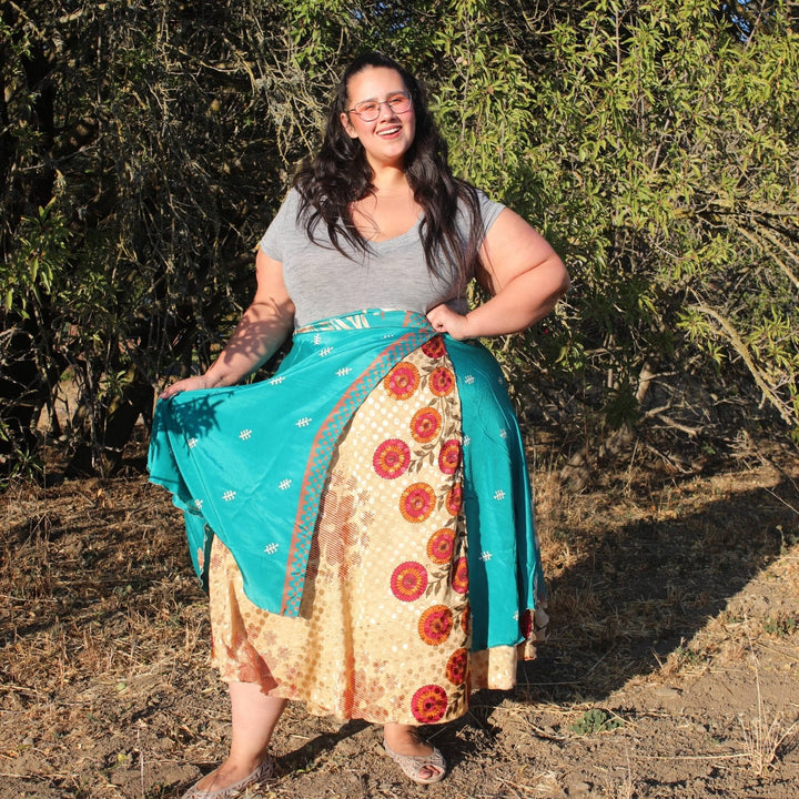 Woman outdoors in a patterned wrap skirt, smiling in a natural setting.