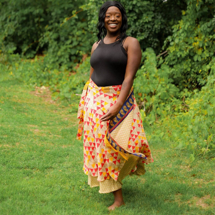 Woman posing in a yellow and red geometric-patterned wrap skirt.
