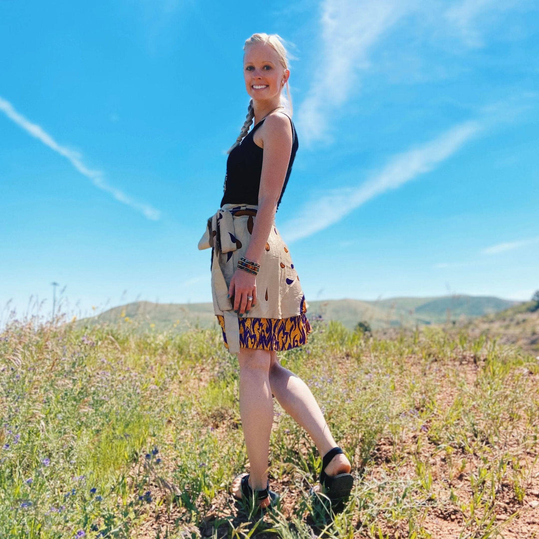 Smiling blonde woman in black top and patterned skirt.