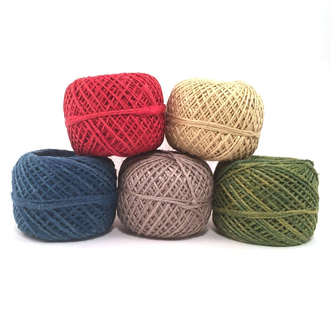 5 cakes of red, blue, beige, yellow and green yarns stacked on a white background