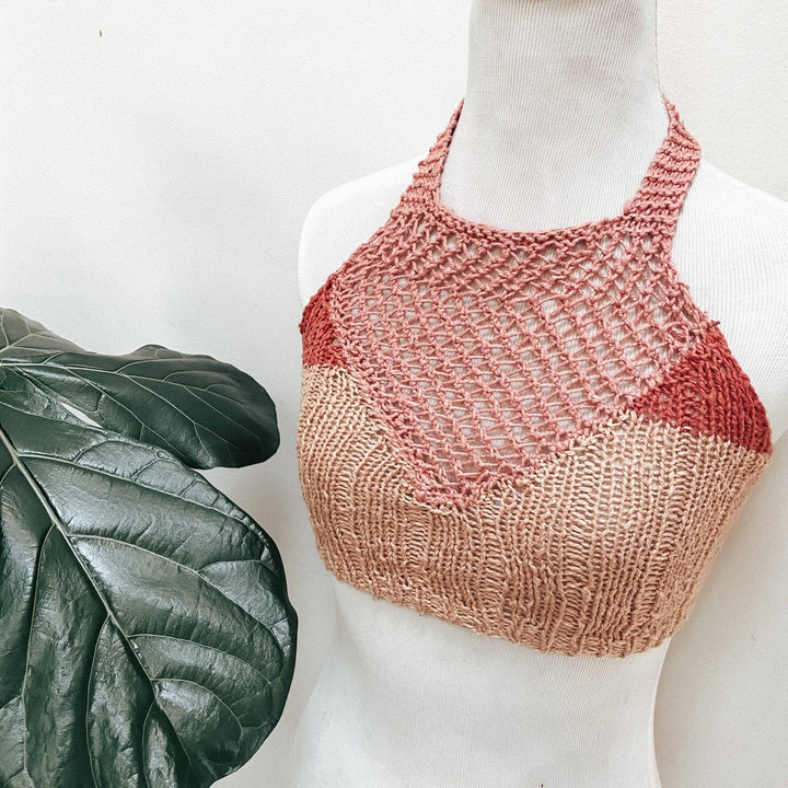 mannequin wearing color blocked pink bralette knit top in front of a white background with a green leaf to the bottom left.