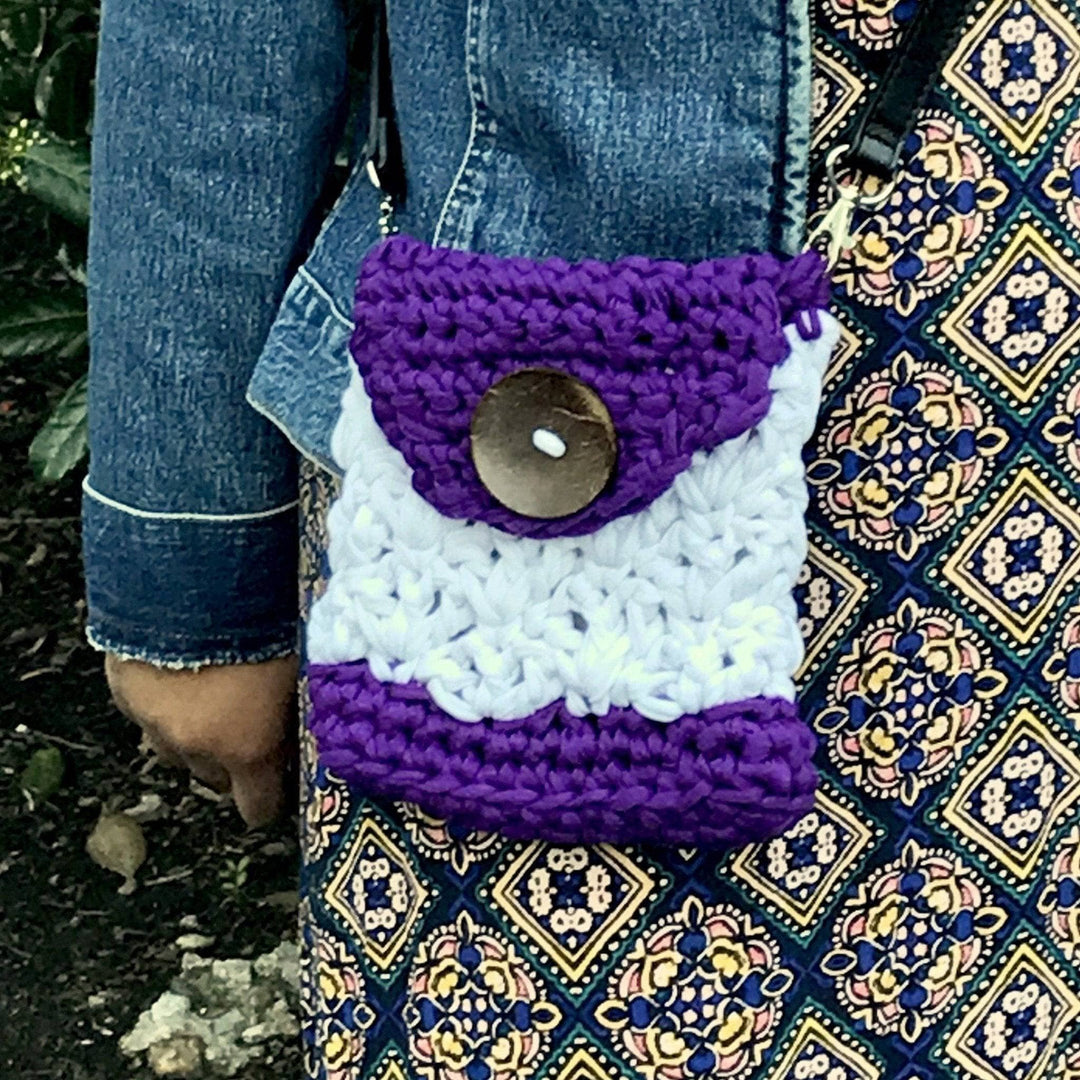 Woman in patterned dress with small crocheted crossbody purple and white bag with large button