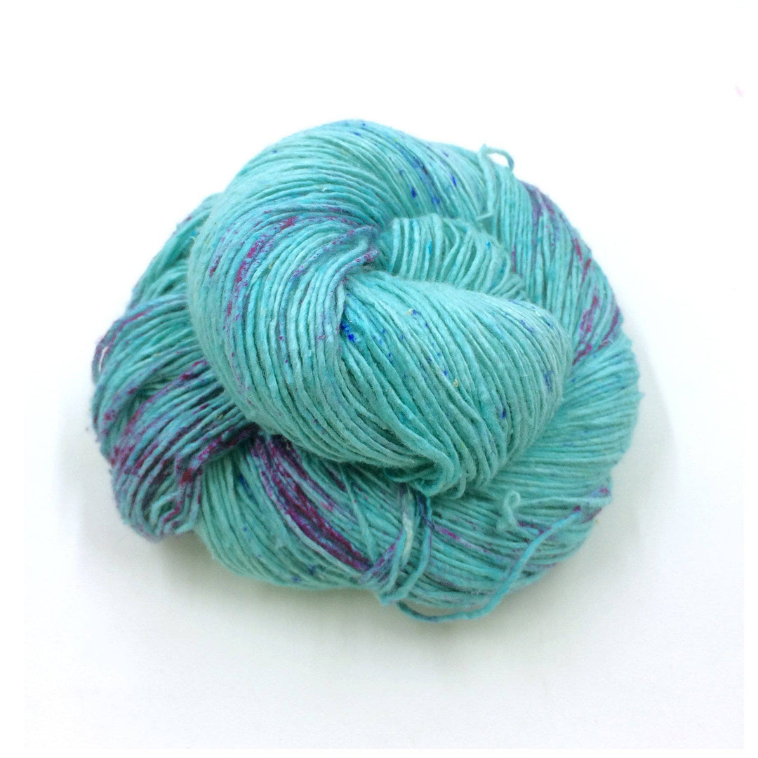 A skein of blue and purple speckled yarn on a white background
