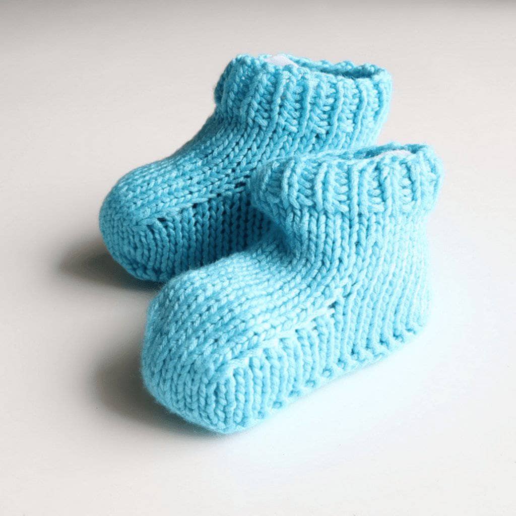 Blue baby booties sitting on a white background