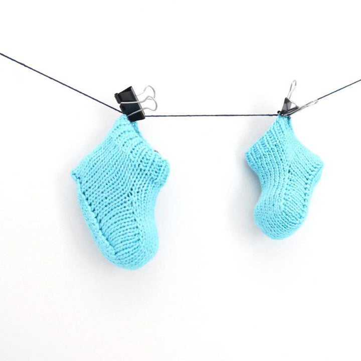 Blue baby booties clipped on a string on a white background