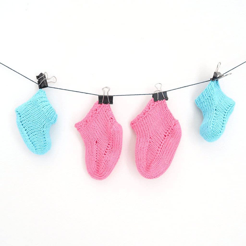 Blue and pink baby booties clipped on a string on a white background