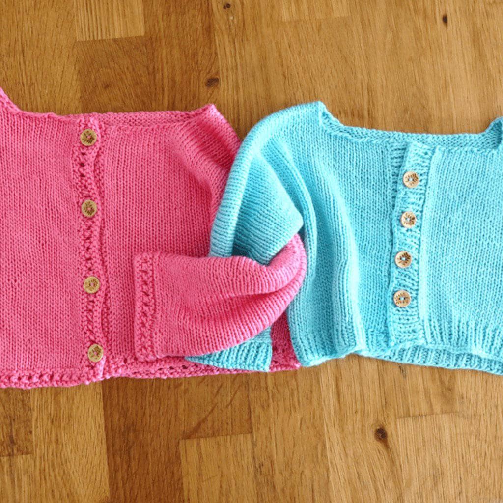 Blue and pink Baby Cardigan on a light wood background