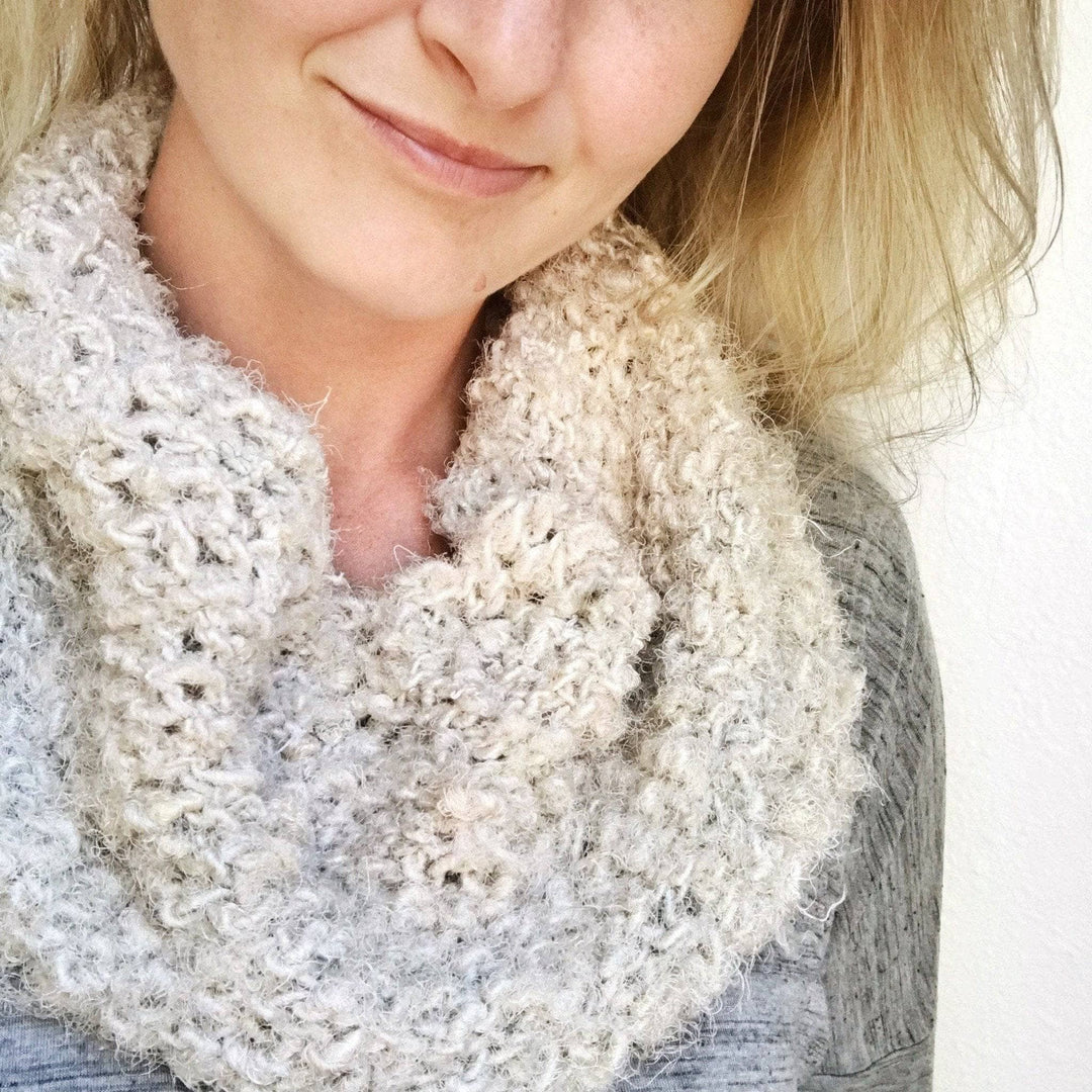 Woman wearing a cream colored knit cowl and gray sweater