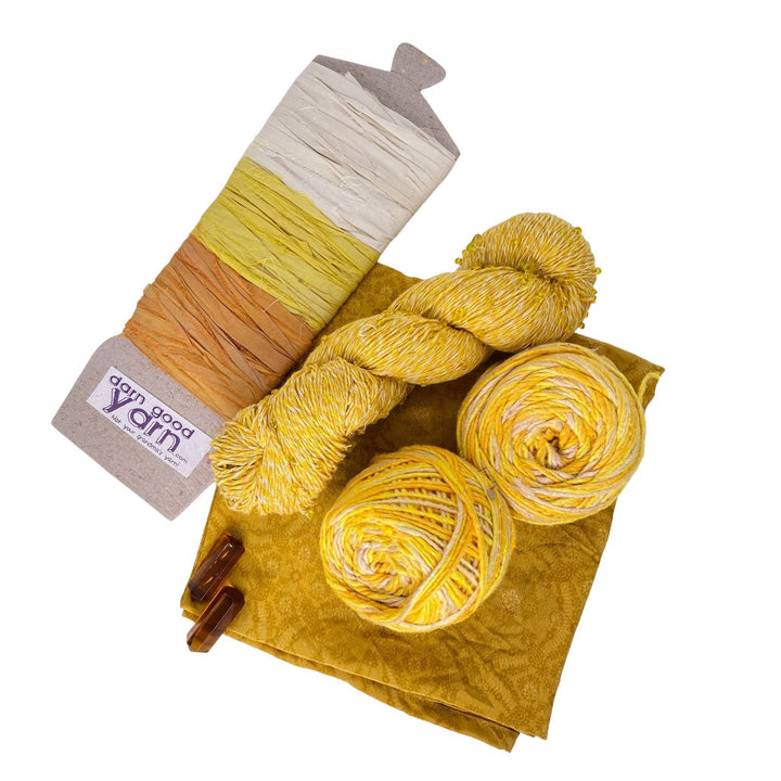 Citrine energy bundle with all items showing in front of a white background. 2 citrine crystals, 2 skeins sparkle worsted weight silk, 1 skeins chakra beaded cotton yarn, 3 color sari silk ribbon sample card, and coordinating furoshiki.