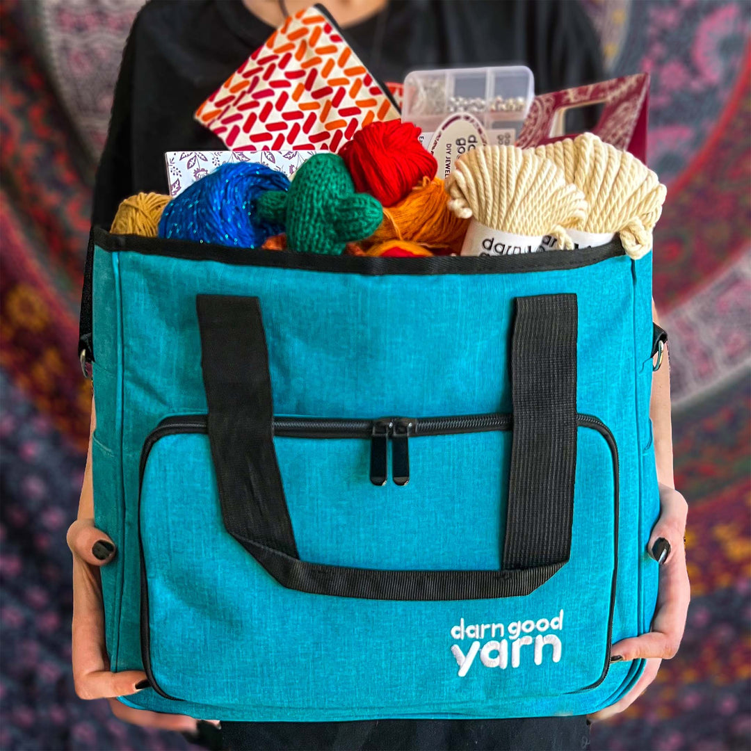 Model is holding the Crafters Deluxe Storage Bag Bundle in teal with contents of bundle filling up the bag.
