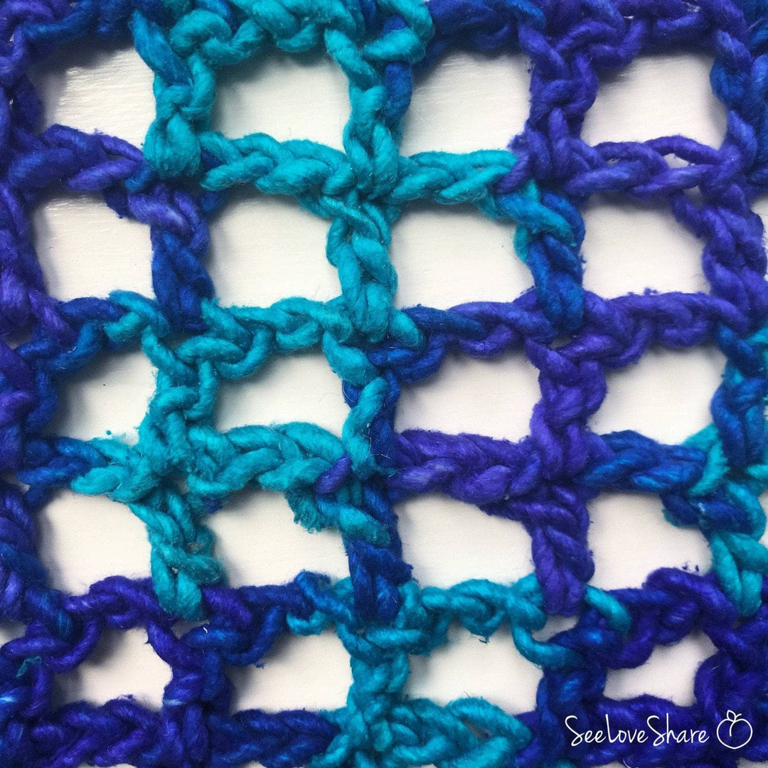 Close up view of a crocheted blue lap blanket