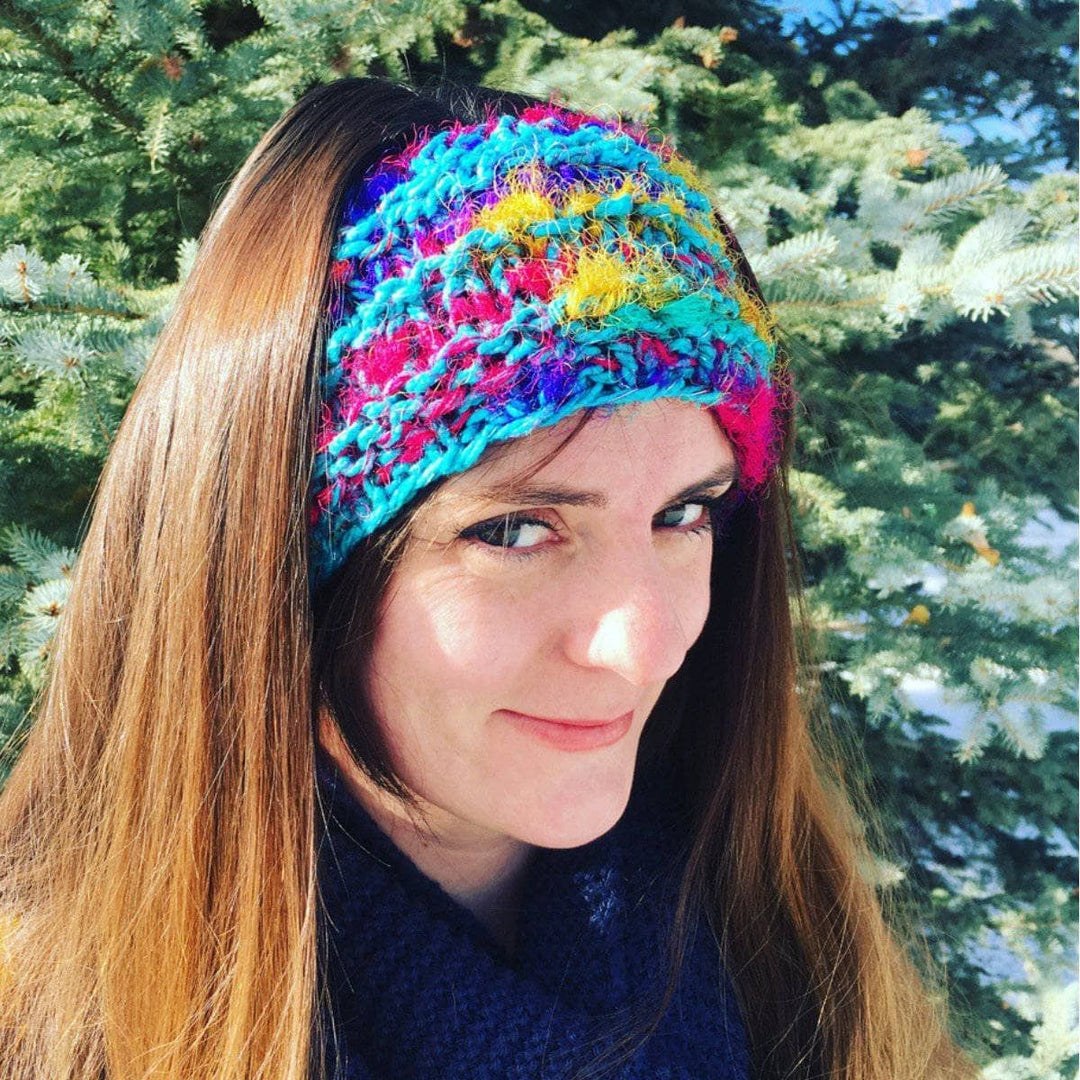 Woman wearing a knit blue multicolored headband standing in front of a tree