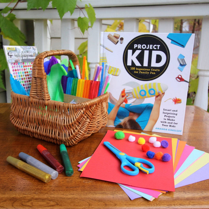 A Kids Project Craft Kit, perfect for winter break projects. This kit has a kids project book, pipe cleanrers, scissors, pom poms, construction paper, sparkle glue and stick on jewels.
