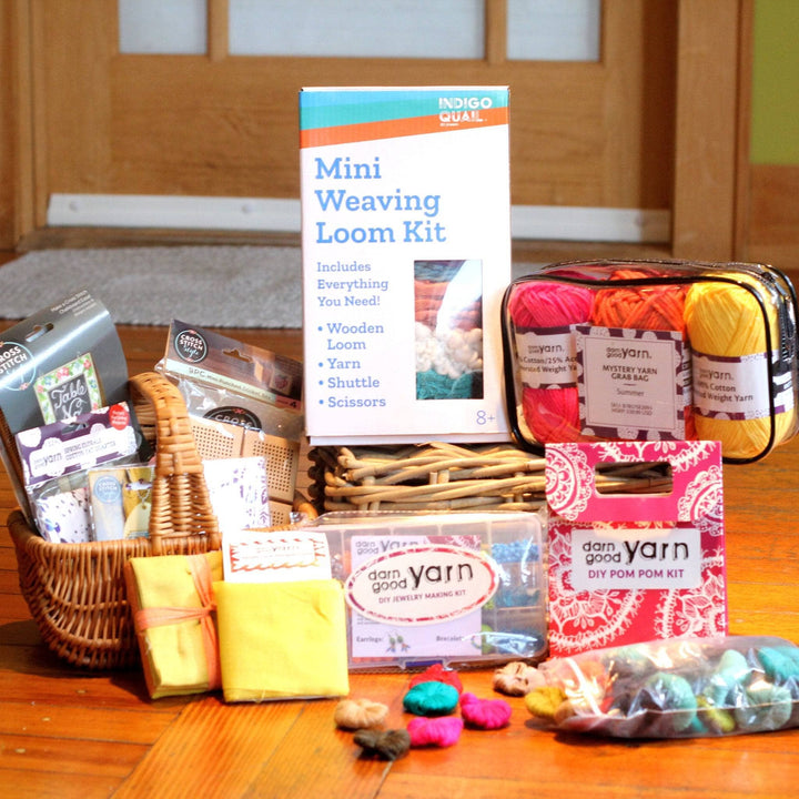 A Kids Project kit for Winter Break. This kit has a mini weaving loom kit, DIY Pom Pom Kit, Fat Quarters, Easy Cross Stitch kits and warm colored acrylic yarns in a travel pouch.