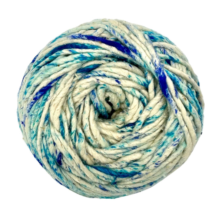 A cake of white worsted weight yarn with blue specks on the yarn on a white background