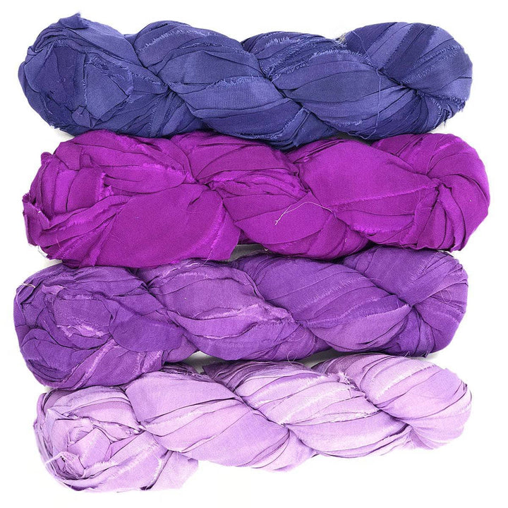 4 hanks of recycled chiffon ribbon yarn in the mumbai colorway (ombre dark to light purple) in front of a white background
