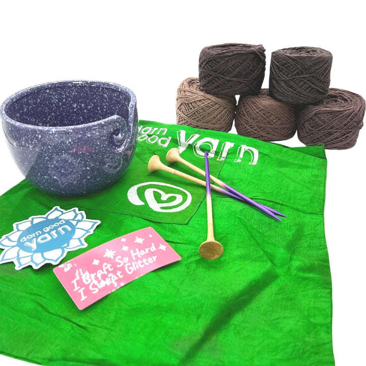 DGY Ceramic Yarn bowl bundle with all items showing in front of a white background. Purple speckled ceramic yarn bowl, dgy sticker pack, US8/5mm knitting needle and crochet hook set, and dk herbal dyed yarn pack in stormy night colorway.