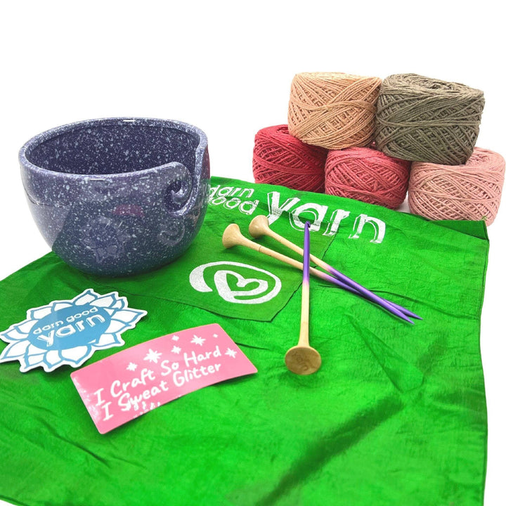 DGY Ceramic Yarn bowl bundle with all items showing in front of a white background. Purple speckled ceramic yarn bowl, dgy sticker pack, US8/5mm knitting needle and crochet hook set, and dk herbal dyed yarn pack in vintage rose colorway.