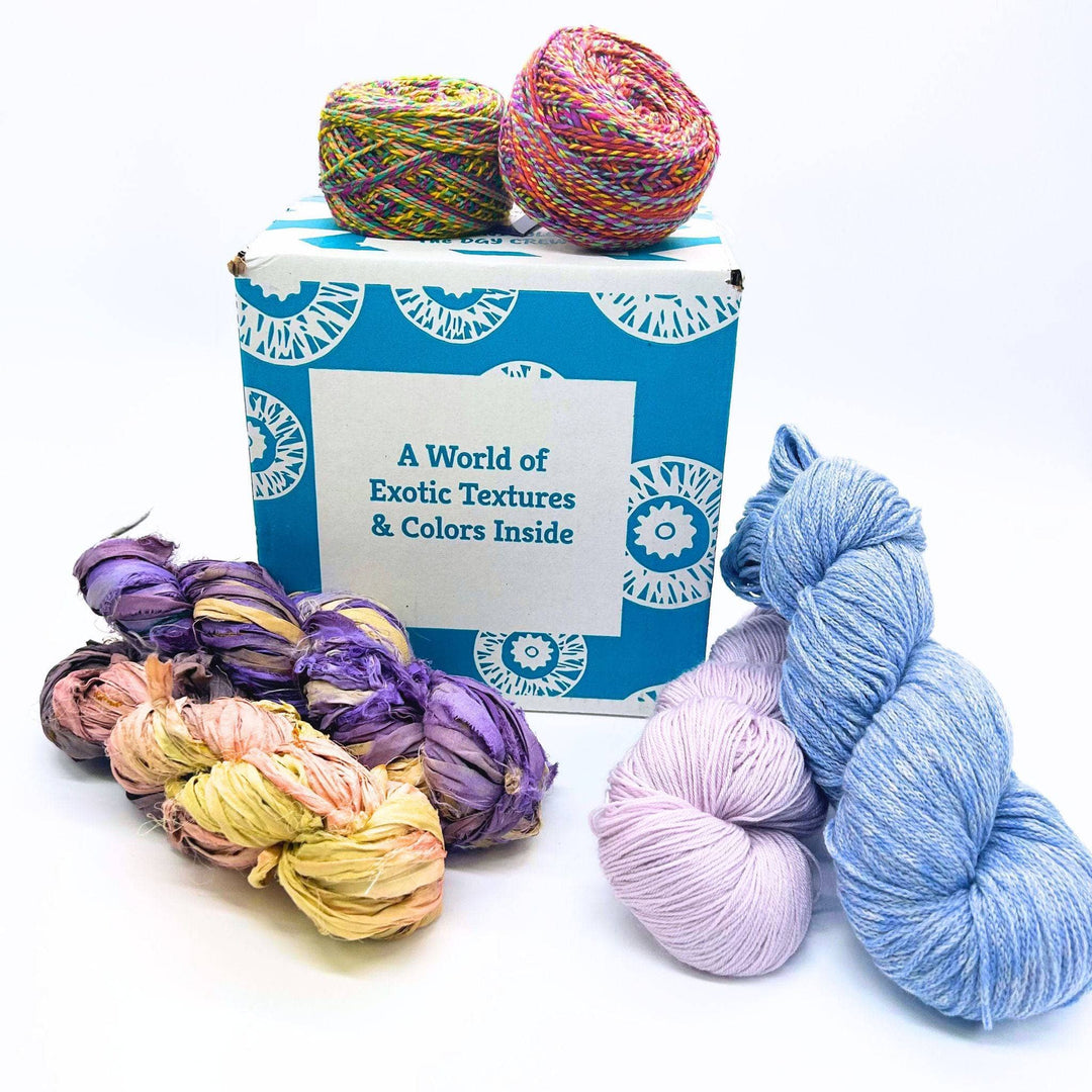 Darn Good Yarn's Editor's Box Mystery Yarn Box pictured with premium recycled silk yarn and ethically-sourced wool yarn