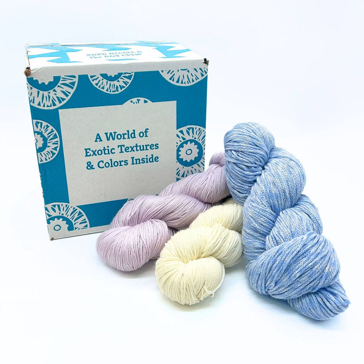 Darn Good Yarn Editor's Box mystery yarn box pictured with Pure Superwash Merino Wool Yarn, Fingering Weight Superwash Merino Blended Yarn, and DK Weight Merino, Alpaca, Cotton Blend Yarn