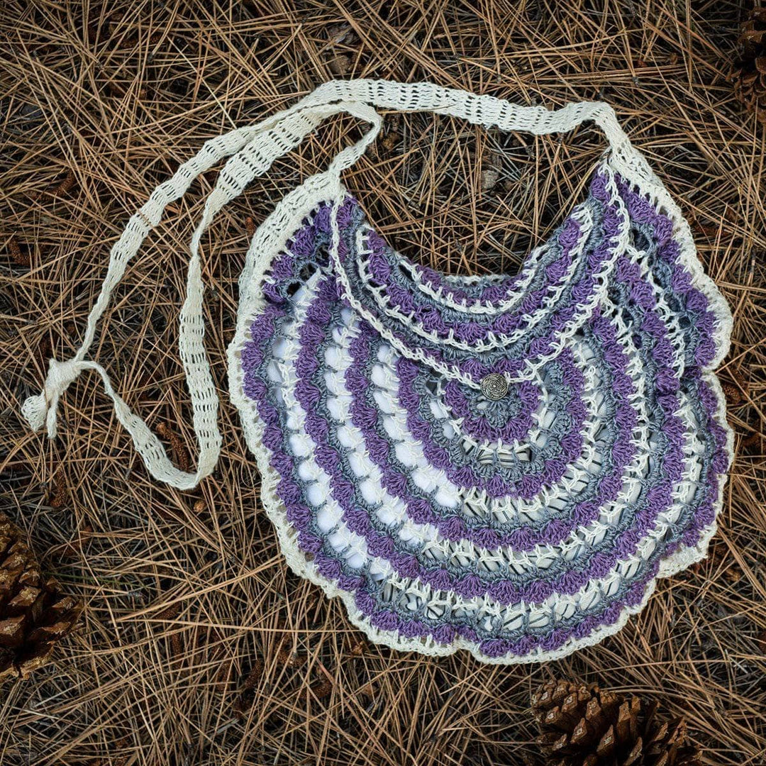 Purple and white mandala pattern crochet bag on a pile of hay