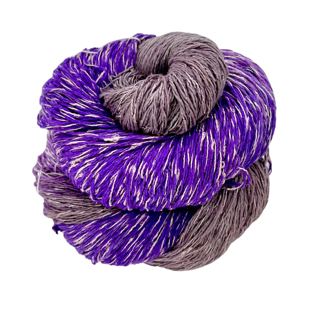 Variegated light and dark purple skein of silk blend sport weight eighty-twenty rule yarn on a white background