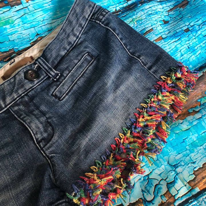 DIY Fringe jean shorts with a wood table that's flaking light blue paint in the background. 