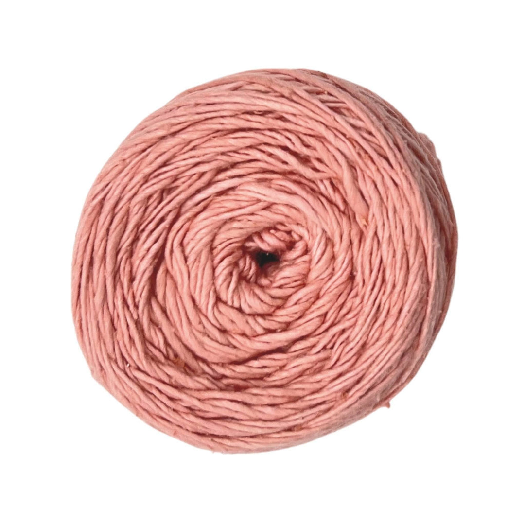 Skein of dk weight recycled silk yarn in front of a white background. Yarn is dyed with natural dyes and is a light pink color.