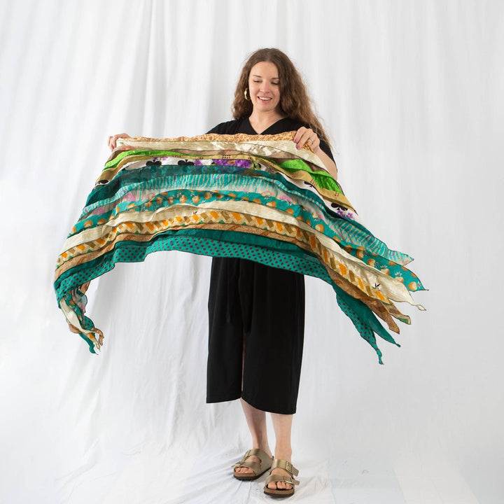 Founder Nicole holding a  earth festival scarf in green and beige in front of a white background.
