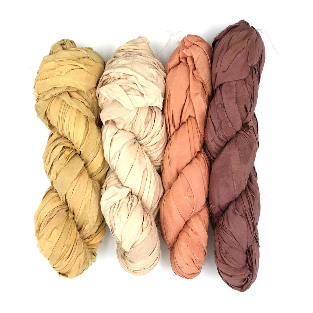 4 skeins chiffon ribbon yarn in neutrals colorway in front of a white background. Left to right: golden tan, light tan, orange tan, brown.