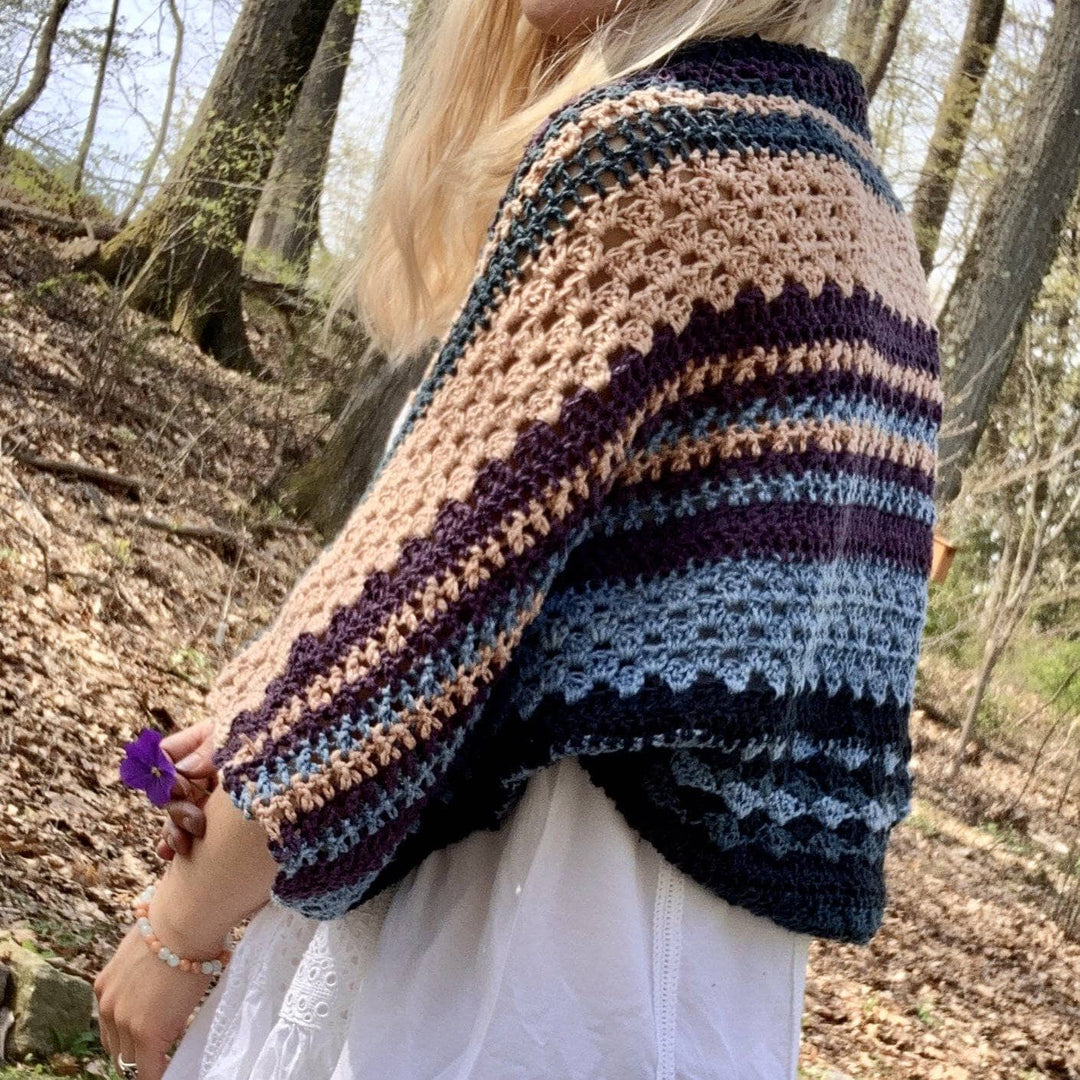 side view of designer wearing ebb and flow herbal dyed shrug outside in the autumn woods.