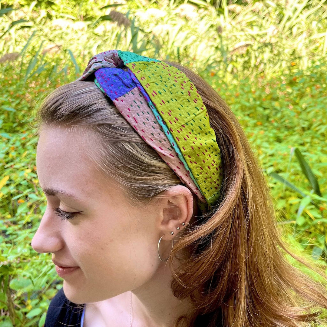 An upclose shot of a kantha stitched sari headband in a womans hair. This headband is mad with cool colors, soft purples, greens and teals.